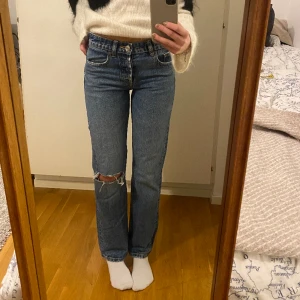 lågmidjade jeans - Lågmidjade blå jeans från zara i flare modell med ett hål som detalj på ena knät. 