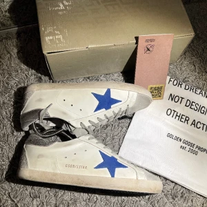 Golden goose skor - Säljer dessa otroliga Golden goose superstar som jag nyss köpt men var tyvärr för små så har bara haft dem några dagar. Dem är skick 8/10. Båda hälarna har defekter som ej syns när skorna är på. Tillkommer: Skor, 1dustbag, box och passport. 