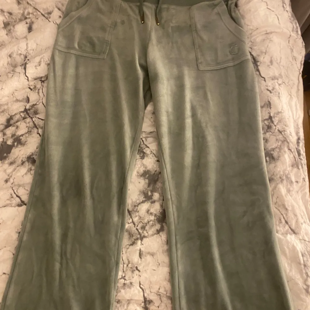 Säljer ett par ljusgröna juicybyxor som är lite urtvättade De är i storleken M Kolla bild 3 för att se hur de ser ut vid fötterna💚. Jeans & Byxor.