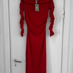 Röd off shoulder långklänning med rynkade ärmar. Perfekt skick då den aldrig är använd (prislapp kvar). 