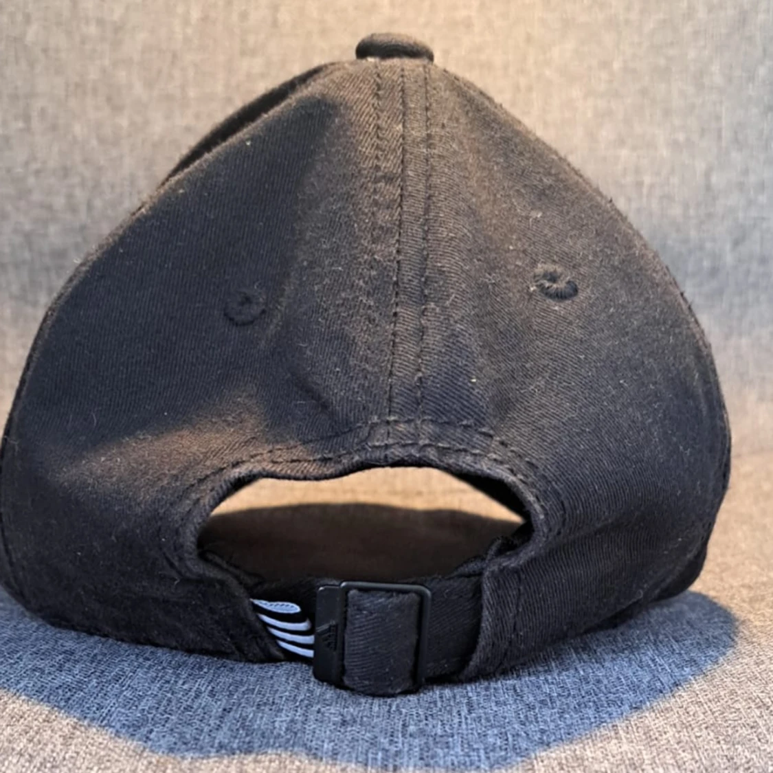 En svart adidas keps med vitt adidas märke och ränder. - 91