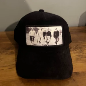 Svart Keps - Svart keps . Osäker på märke men kan vara maggiore. Spännet är lite trasigt men påverkar inte funktionen! Mvh Liam