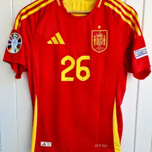 Spaniens matchtröja för sommaren EM  2024 med Pedri på ryggen. Tröjan är en reprint i nyskick med emblem och patchar av högsta kvalité. Storlek: Medium. Tröjan är en player version vilket är den tröja som spelarna själva använder. Tajt i storleken.