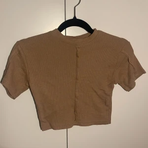 Beige tshirt - Varm beige färg. Aldrig använd så ny och fint skick. Märke public desire. Mjukt och skön material, sitter tight och inte pösigt.