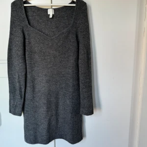 Stickad klänning  - Stickad klänning från H&M, storlek M. Gråmelerad. Figursydd. Kort. Normal i storleken. Endast provad.  Pris kan diskuteras, kom med förslag