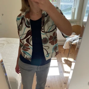 Retro Topp - Suuperfin och cool vintage topp med retro-tryck! Toppen är i jättefint skick och passar nog storlekar från xs till m beroende på hur man vill att den ska sitta. Kort i modellen, har en fin krage och har knäppning fram längst ner. 🌺🌺🌺