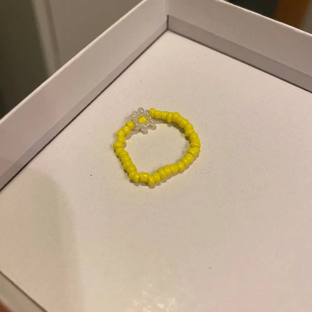 En söt gul ring med vit blomma av pärlor! Fint skick. Accessoarer.