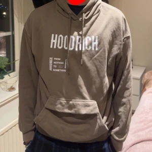 Hoodrich Hoodie - En mörkbeige hoodrich hoodie i storlek M , hoodien är i fint skick men knappen vid magen är sönder men det är inget som märks. Hoodien passar till alla tillfällen. Hoodien är limited edition och finns inte att köpas längre i butik. 