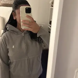 Jätte fin grå zip hoodie från Ralph lauren. De snygga och unika me denna hoodien är att den har slits på sidorna som gör att den sitter jätte snyggt på!