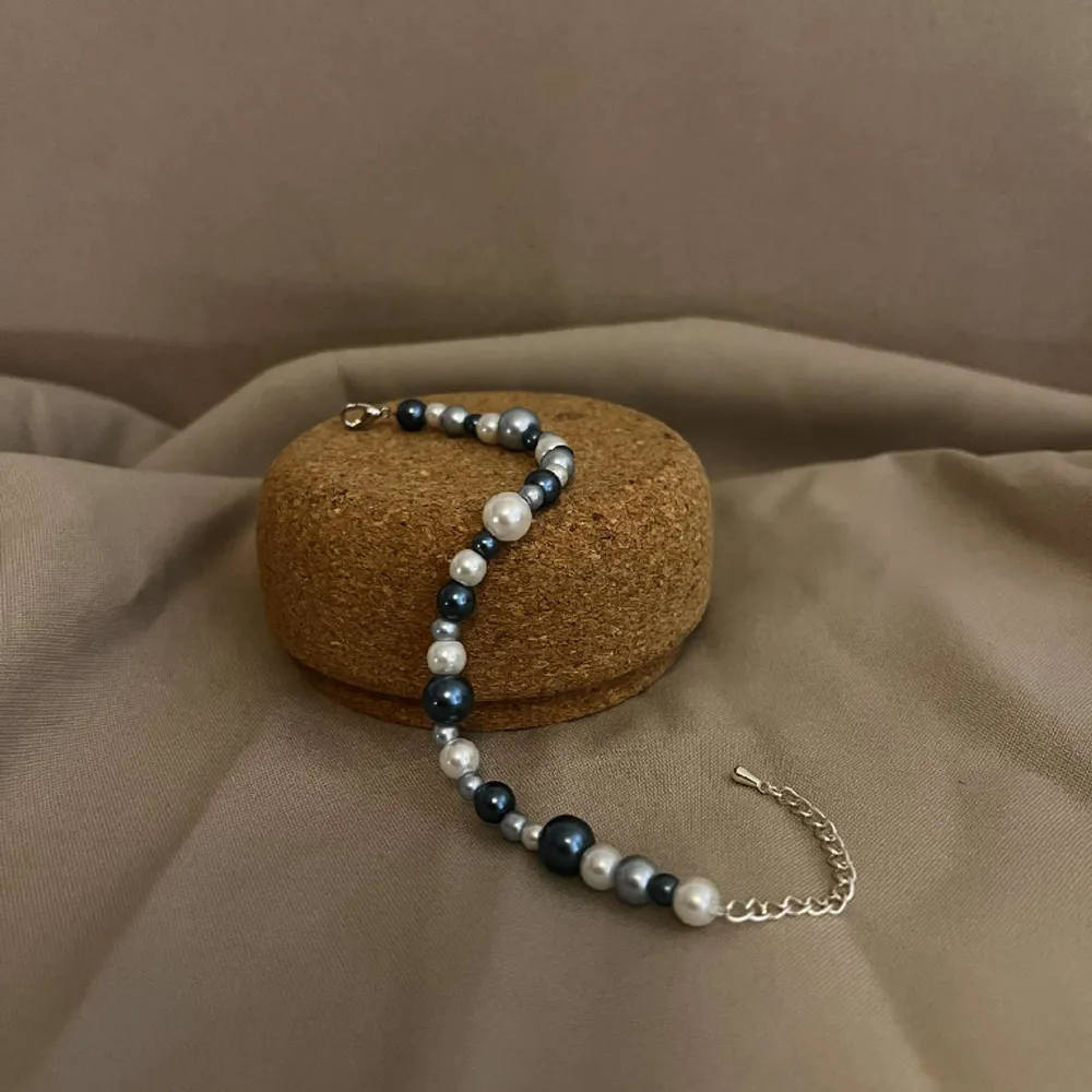 Armbandet Eleonore består av flera olika storlekar av pärlor i olika färger av blått med silver lås och kedja.  Namn: Elonore Längd: Hela 23 cm Pärlor 15,5 cm. Accessoarer.