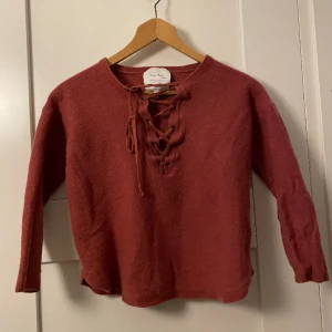 Stickad tröja - Fin stickad tröja i korall färg med snörning där fram. Storleken är L men den passar mer som XS/S