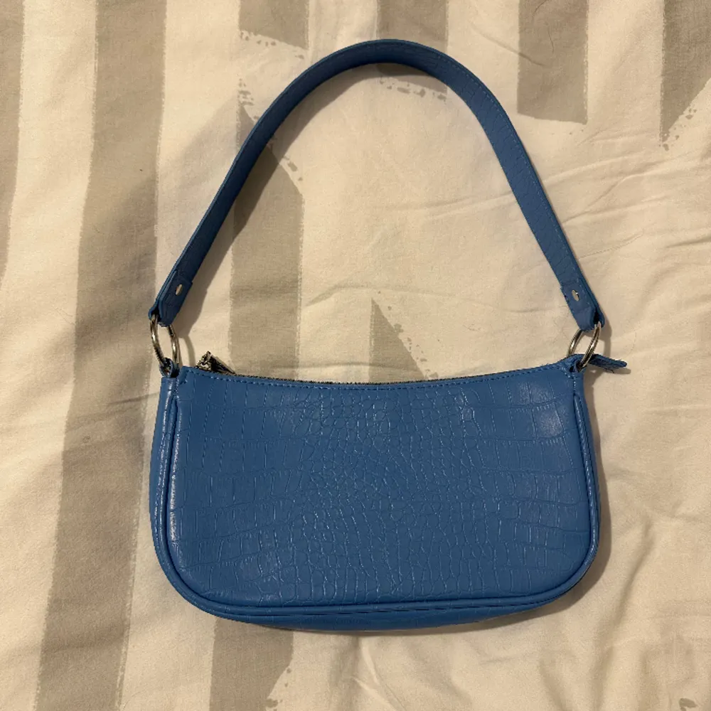 En väska från H&m i en jättefin blå färg, jättefin till sommaren. Aldrig använd så fint skick. . Väskor.