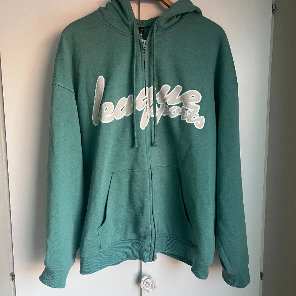 en grön/turkos hoodie från hm med stort tryck fram, använd men bra skick, sitter lite oversize på mig som brukar ha strlk 46/XL . Hoodies.