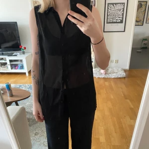 Skjorta - Genomskinlig svart armlös skjorta. Svarta pärlor på kragen. Från soyaconcept 