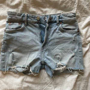Ljusblåa jeansshorts med hål från zara - Mid waist jensshorts från Zara. Fint skick Storlek xs