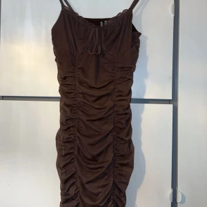 Rynkad Kort Klänning - Detta är en jättefin kort klänning i brun! Jag har endast använt den 2 gånger och den är i samma skick som när jag köpte den💕 Anledningen till att jag säljer den är för att jag inte får användning av den längre men den är fortfarande supersnygg!!