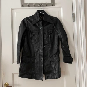 Skinnjacka - Svart skinnjacka med knappt och lite kortare ärm. Köpt på secondhand för 800 kr. Använd en gång av mig. Mycket fint skick. Står ingen storlek i men skulle gissa på XS-S. Bara att fråga om det är något du undrar! 