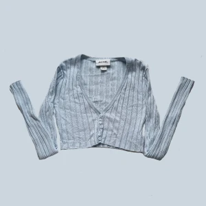 Långärmad tröja - En ljusblå croppad, och ribbad långärmad tröja med knappar längst fram. Köpt på plick men jag har inte använt den och den är i väldigt bra skick. Den är också väldigt strechig så den passar upp till s/m, trots att den är skriven att vara xxs. 