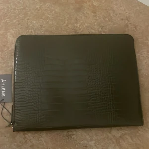 Datorfodral  - Datorfodral, aldrig använd (helt ny köpt).  Färg: Skogsgrön (khaki) Prislappen sitter kvar, köpt på Åhléns outlet och produkten säljs inte längre.