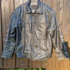 Woodlands läder jacka - Svart läder jacka med ett utslitet utseende. Tillkommer två spännen vid var sida, samt en bröstficka och även en innerficka. Skick är (7/10). Det felas en bit av handtaget på löparen men blixtlåset fungerar felfritt. Godtar yttligare frågor om 💰&📏