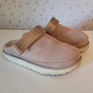 Snygga och bekväma UGG-tofflor i beige, färgen heter Driftwood.  Storlek 38.  Fint skick, sparsamt använda. Svarar gärna på frågor eller skickar fler bilder