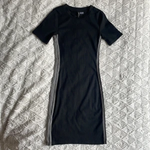 Klänning - Säljer denna svarta klänning. Formar kroppen fint med detaljer på sidan.