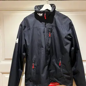 Storlek M. Mycket fin och klassisk jacka från Helly Hansen som är både vatten och vind tät. Skicket är som ny. Nypris Ca 2000kr. Vårt pris 375kr + frakt.  Känner ni för att köpa flera produkter samtidigt kan vi komma överens om paketpriser och frakt🤝