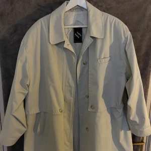 Oversize beige/vit vårkappa  - Perfekt vår och höstkappa. Köpt second hand så vet varken märke eller storlek. Men skulle säga L för oversize fit och XL för normal fit.  Använd men i gott skick!  Kika på mina övriga annonser så samfraktar jag gärna :)!