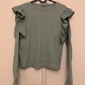 Tröja med volanger  - En turkos färgad tröja med volanger vid axlarna från Maria Serneholts kollektion. Storlek 164, passar mig som har storlek S. Använd ett par gånger men i väldigt fint skick! 130kr, köparen står för frakten🩵🫶🏼