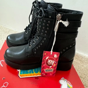 Svarta kängor med detaljer från XTI kids - Fina svarta kängor från XTI kids med detaljer. Oanvända. Jag beställde fel storlek och hann inte skicka tillbaka så därför säljer jag de. Lappen är alltså kvar. Helt nya i nyskick. 