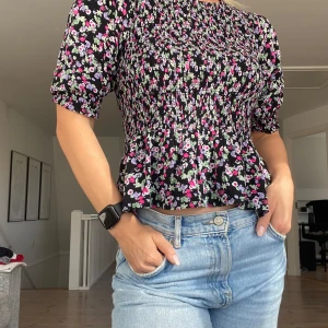 Blommig top - Blommig top, åtsittande med volang och puffärmar. Sparsamt använd!