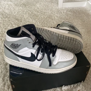 Air Jordan 1 mid ’Light smoke grey’ - Skorna är i fint skick och använda med omsorg. De har inga skador men de är använda. Färgen är grå, svart och vit. Sko kartongen som ni ser på bilden är borta.