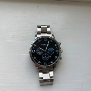 Klocka herr silver Geneva - Snygg klocka från Geneva. Klockan är i fint skick utan skavanker dock går klockan lite konstigt så den bör endast användas som smycke, därav priset. Storleken går att justera.