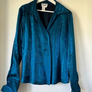 Skjorta i blå metallic - Metallic blå skjorta från märket script. Köpt på beyond retro och är oanvänd sen dess. I mycket gott skick, prislappen kvar. I storlek M/38/10