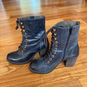 Svart klacksko - Säljer dessa svarta klackar från Vagabond! Skorna är i äkta skinn med en bred klack, dragkedja och snörning med guldiga detaljer. De är i storlek 38 och bra skick! 