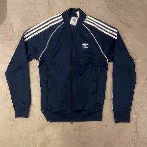Adidas track zip up - Mörkblå/navy Slim fit storlek Small Adidas tracksuit zipup i prima skick. Den är kraglös och har resorer runt midjan så den sitter rätt tight. 