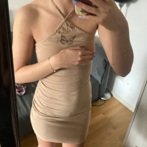 Sommarklänning fjärilstryck - Säljer denna beiga sommarklänning med ett fint fjärilstryck vid bröstkorgen! Använder inte pga att den inte riktigt är min stil.