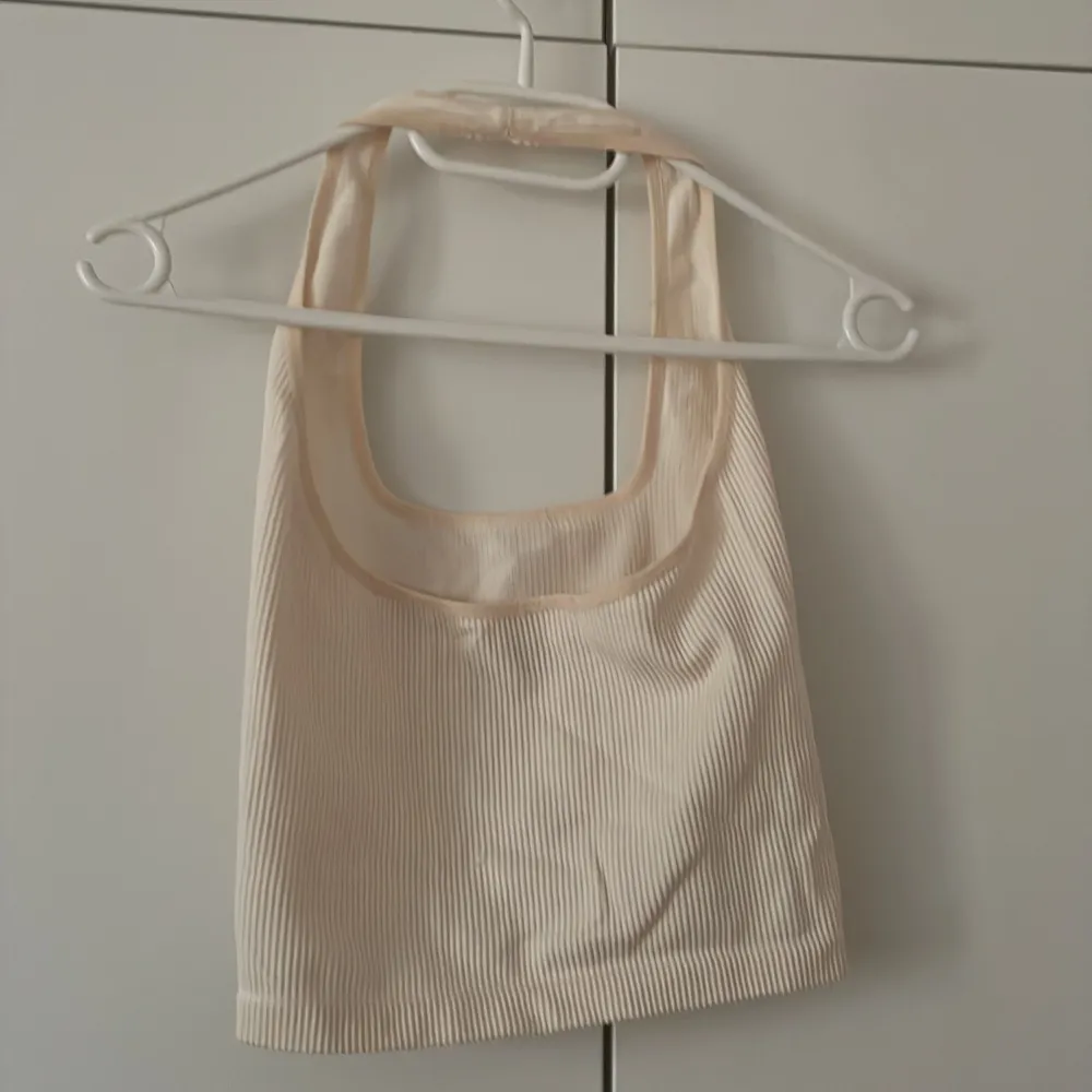 En beige ribbad halterneck topp från Urban outfitters. Storlek S. Bra skick, liten defekt (liten ”repa” som knappt syns) på ryggen.. Toppar.