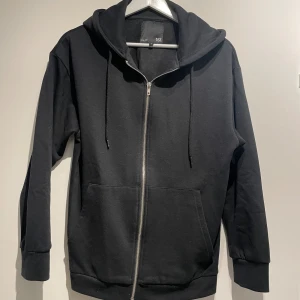 Svart huvtröja med dragkedja  - Säljer denna svarta huvtröja med dragkedja från lager 157, aldrig använd. Storlek S