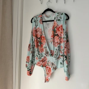 Body med blommor  - Långärmad body med blommor i storlek S. Från Nelly. 