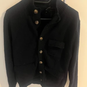 Stickad Cardigan Från Sand - Väldigt snygg o mysig cardigan från Sand. Det är hög kvalité på tröjan och den sitter väldigt bra. Själva lappen är av på ena sidan men det är inget man ser ser när man bär tröjan. Mitt pris: 1199kr Nypris: ~ 3000kr Om ni har fler funderingar, skriv!