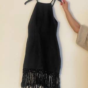En svart stillig, stickad strandklänning. Har använts ett antal gånger, men är i bra skick. Finns dragkedja till höger om klänningen. 