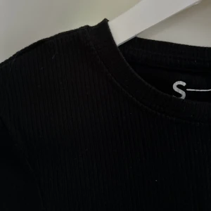 Croppad svart T-shirt  - En något croppad svart T-shirt, den är från new yorker! Riktigt skön och har inga defekter då den knappt är använd! 