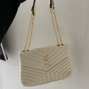 Ysl väska  - ”Ysl” väska som aldrig kommit till användning! In en beige/vit fin färg med guld detaljer. Köpt utomlands för några år sedan men är oanvänd 