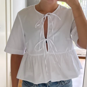 Vit poplinblus - Vit blus med knytning o volang i storlek 36. Prislapp avklippt o blusen är använd en gång. Säljer då jag har en liknande. Inga defekter. Blusen är i bomull. 