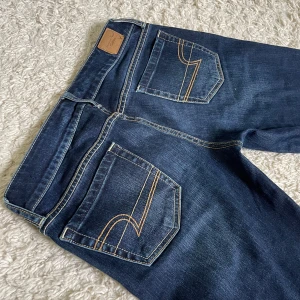 Vintage American Eagle Jeans - Vintage jeans från American Eagle med supersnygg färg och detaljer. Dessutom i perfekt skick! 😍 Rakare bootcut och låg midja! ❤️ Innerben och midja ser ni på bild, men kontakta mig gärna ifall ni vill ha flera mått. Jag är 167 och de är stretchiga. 🫶🏻