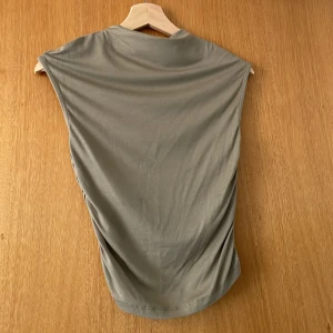 Grön fintopp - En otroligt fin tröja med ”scrunch” längst sidorna och en fantastiskt färg, som tyvärr inte kommer till användning. Använd en gång.