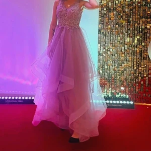 Balklänning  - Balklänning helt oanvänd. Stl Xs passar 160cm.  Rosa/ lila färg och paljetter. Väldigt fin! 