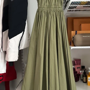 Michael Kors klänning - En klänning från Michael Kors i nyskick, oanvänd. Etiketten finns fortfarande kvar. Lång ärmlös klänning med lätt utsvängd linje med lock i midjan och utskuren baktill. Färgen är i Smoky Olive och klänningen är i storlek XS men passar S. 