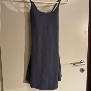 Klänning med inbyggd bh och shorts, strl M - Säljes i väldigt fint skick. Längd 83cm Byst 38cm Midja 35 cm (mycket stretch i tyget så ca 35-45cm beroende på hur tight man vill ha den) Shortsen och bh sitter ihop, det är alltså som en ”hold in” jumpsuit under klänningen.  77% nylon  23% elastane